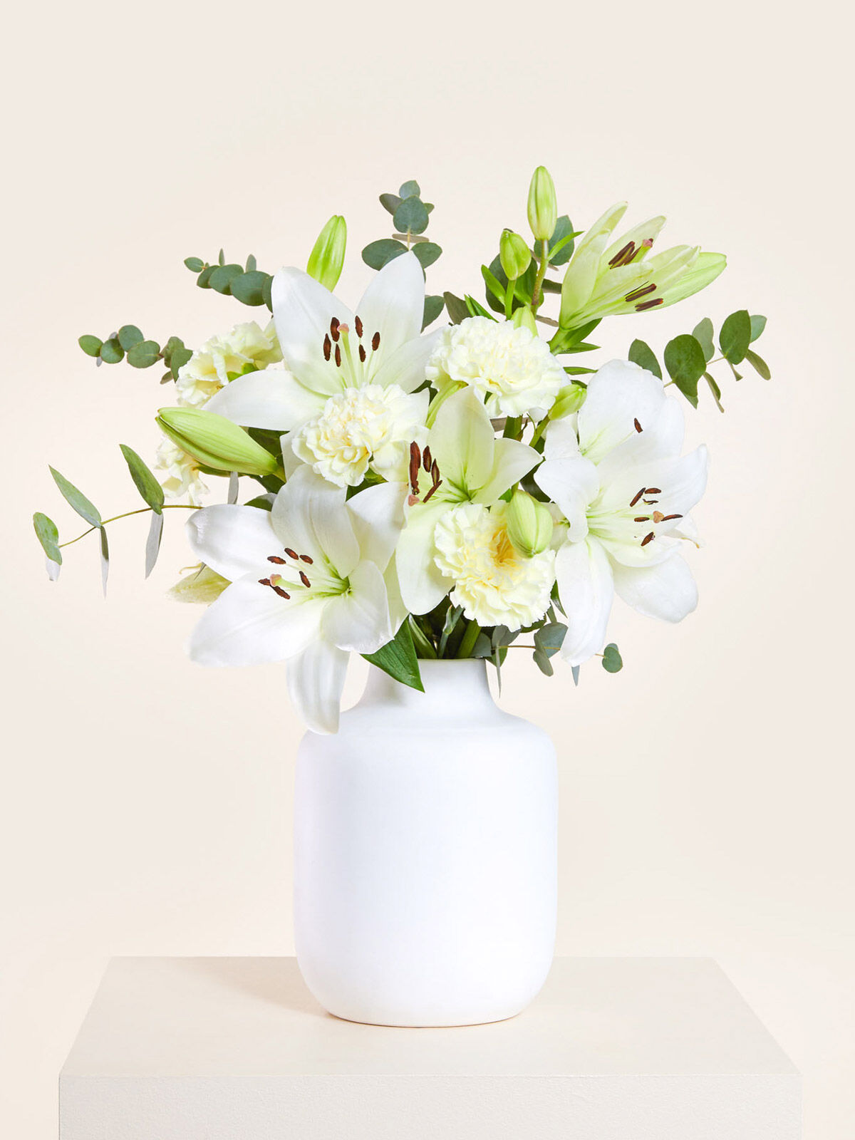 Ich denk an Dich Weiße Nelken Lilien und grüner Eukalyptus sind arrangiert in einer weißen Keramikvase