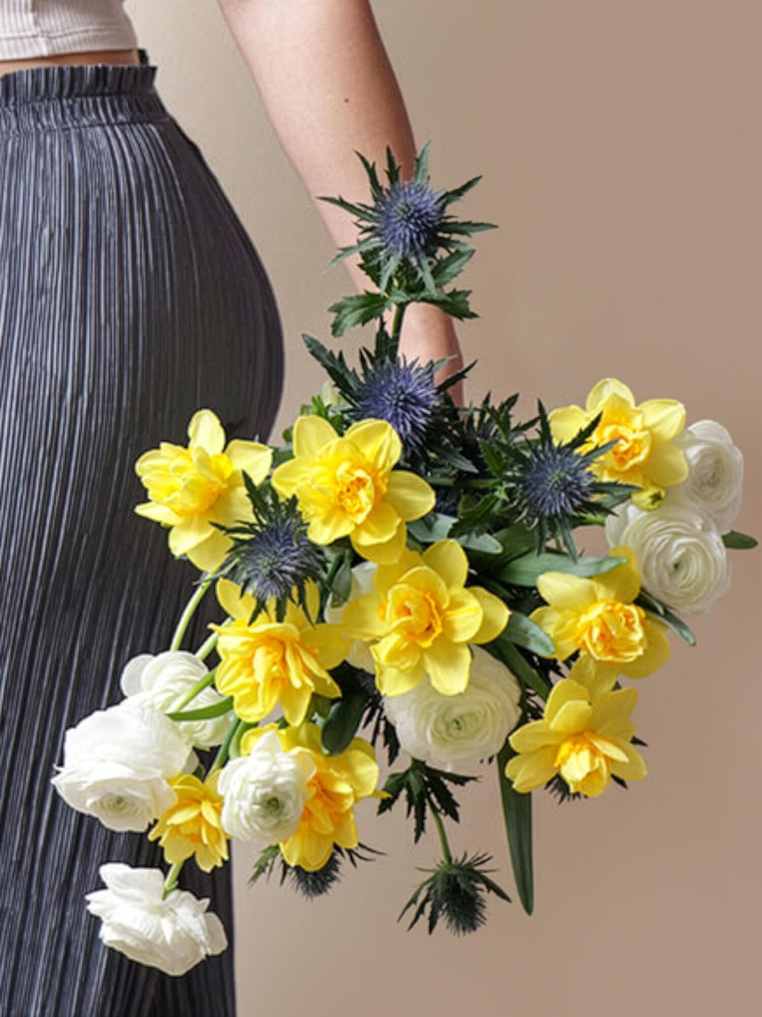 Blumenstrauß, gelbe Blüten, weiße Ranunkeln, blaue Disteln, gedämpfter Hintergrund